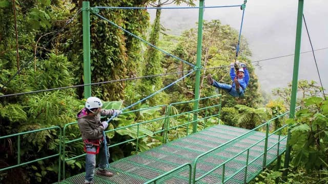 Traveler enjoying a zip line adventure while guide helps