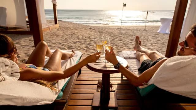 Couple at the beach drinking a cocktail in beach chairs