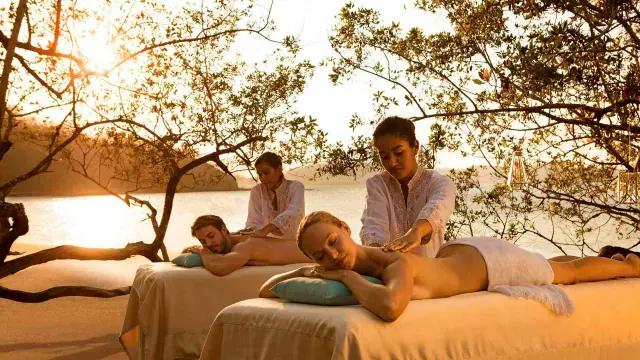 Couple enjoying a massage together on the beach during the sunset