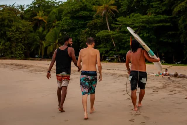 Three friends carrying their surfboards in Puerto Viejo