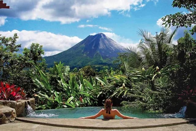 Woman enjoying a pool with Arenal Volcano views in The Springs Resort