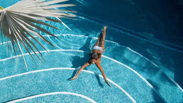 Girl swimming underwater in a sunlit pool