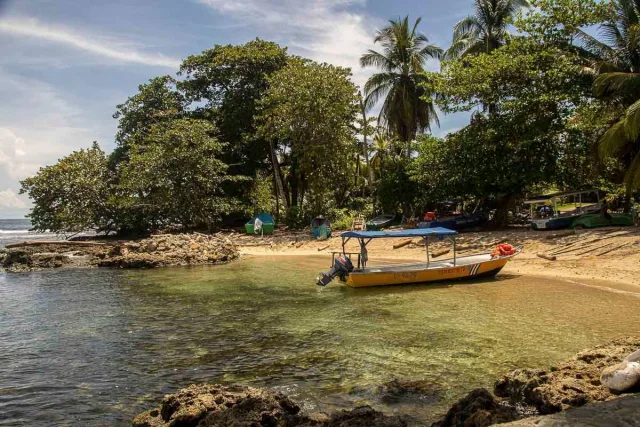 Boat decked on a beach in Puerto Viejo surrounded by green tropical trees